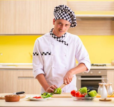 Genç profesyonel aşçı mutfakta salata hazırlıyor.