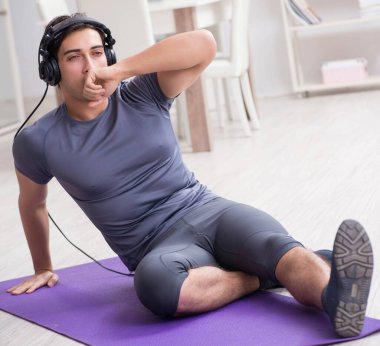 Adam evde spor yapıyor ve müzik dinliyor.