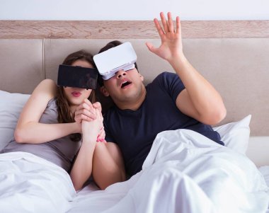 Yatakta sanal gerçeklik gözlüklü eş ve koca.