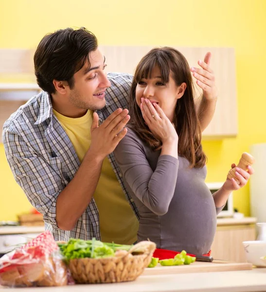 Man och gravid kvinna tillagar sallad i köket — Stockfoto