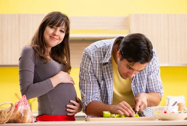 Hombre y mujer embarazada preparando ensalada en la cocina —  Fotos de Stock