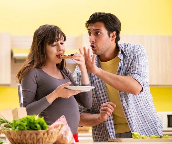 Man en zwangere vrouw het bereiden van salade in keuken — Stockfoto