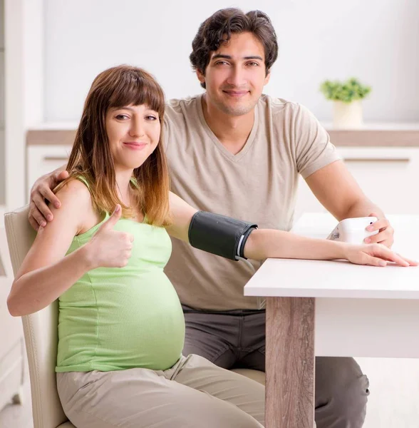 A férj ellenőrzi a terhes feleségek vérnyomását — Stock Fotó