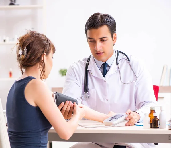 Jovem médico verificando a pressão arterial das mulheres — Fotografia de Stock