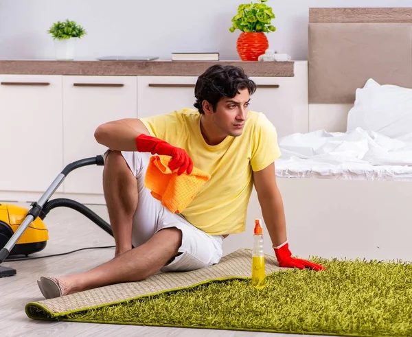 Giovane uomo bello pulizia in camera da letto — Foto Stock
