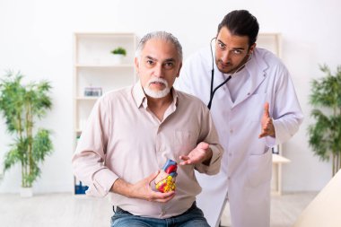 Yaşlı adam genç doktor kardiyoloğu ziyaret ediyor.