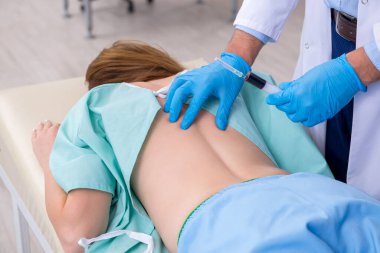 Genç sırtı yaralı kadın, erkek doktor masörünü ziyaret ediyor.