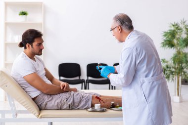Yaralı adam ilk yardım konseptinde yaşlı doktoru ziyaret ediyor.