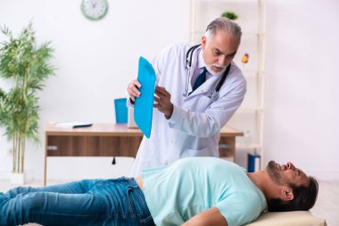 Yaralı genç adam yaşlı doktoru ziyaret ediyor.