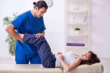 Yaralı kadın genç erkek doktor osteopat 'ı ziyaret ediyor.