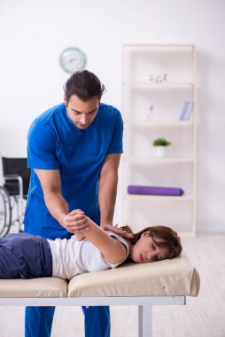 Yaralı kadın genç erkek doktor osteopat 'ı ziyaret ediyor.