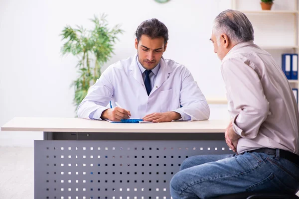 Velho paciente visitando jovem médico masculino — Fotografia de Stock