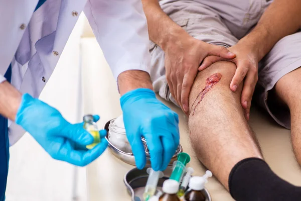 Benskadad man besöker gammal läkare i första hjälpen koncept — Stockfoto