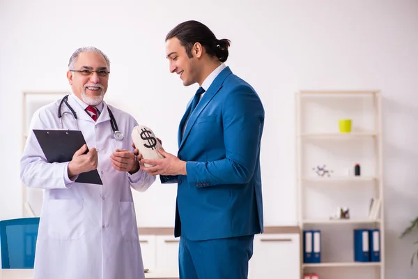 Jeune homme d'affaires rencontre avec un vieux médecin — Photo