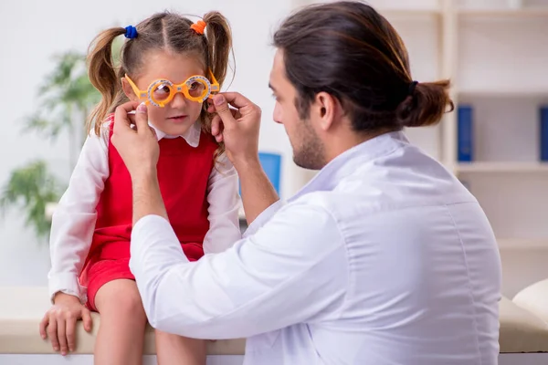 Menina pequena visitando jovem médico oculista masculino — Fotografia de Stock