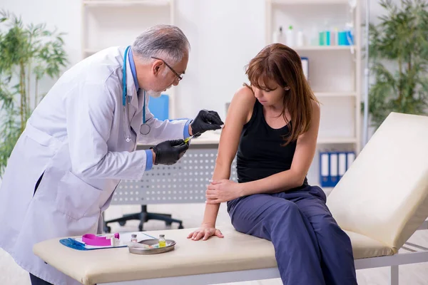 Jovem mulher visitando velho médico masculino — Fotografia de Stock