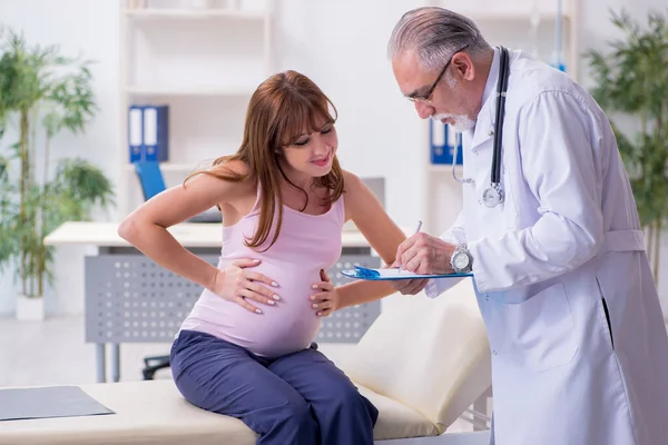 Jovem mulher grávida visitando velho médico ginecologista masculino — Fotografia de Stock