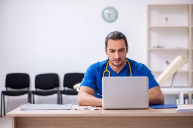 Klinikte çalışan genç erkek doktor.