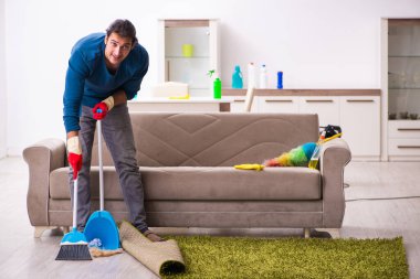 Genç adam evde ev işi yapıyor.