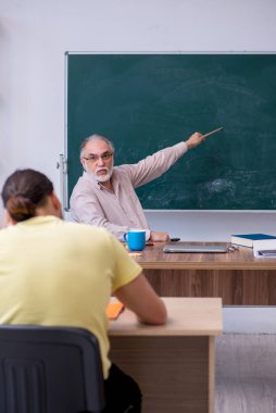 Yaşlı öğretmen ve genç erkek öğrenci sınıfta.