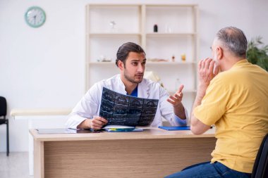 Yaşlı hasta, genç erkek doktor radyolojisti ziyaret ediyor.
