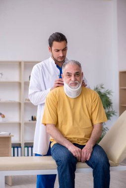 Yaşlı boynu yaralı bir adam genç erkek doktoru ziyaret ediyor.