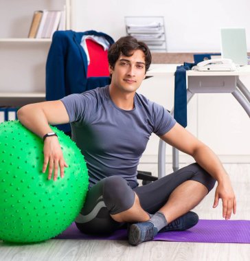 Ofiste egzersiz yapan genç bir erkek.