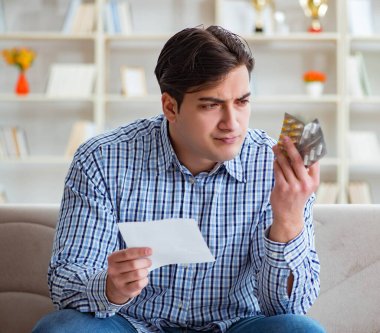 Kanepede ilaç ve reçeteyle oturan genç adam.