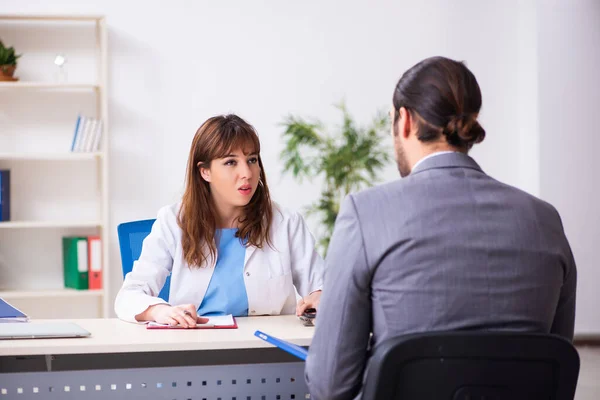 Young female doctor and sick businessman in the office — Stock Photo, Image