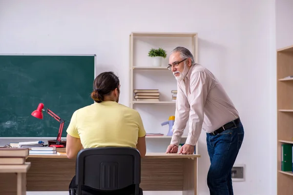 Viejo profesor y joven estudiante masculino en el aula — Foto de Stock