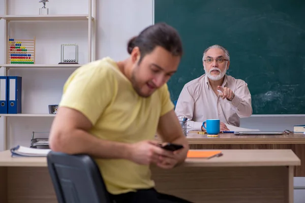 Old teacher and young male student in the classroom — Stock Photo, Image