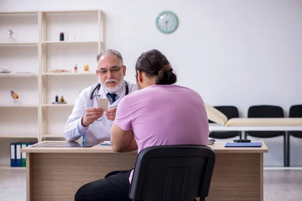 Ung manlig patient besöker gamla manliga läkare — Stockfoto