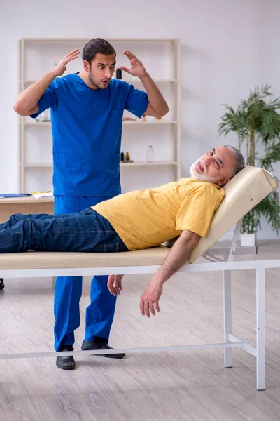 Old patient visiting young male doctor — Stock Photo, Image