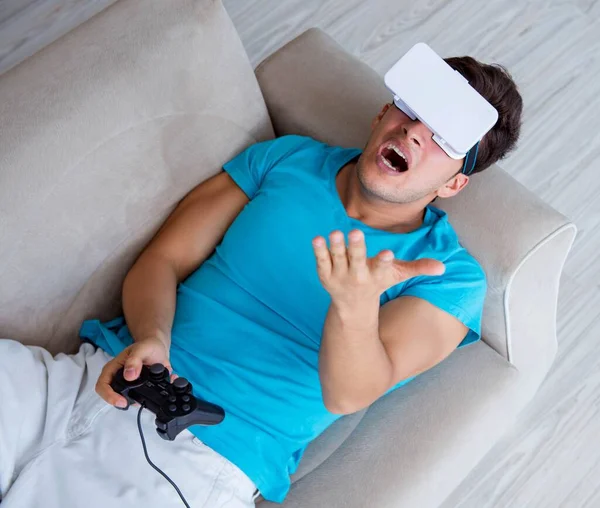 Hombre joven con gafas VR relajándose en sofá —  Fotos de Stock