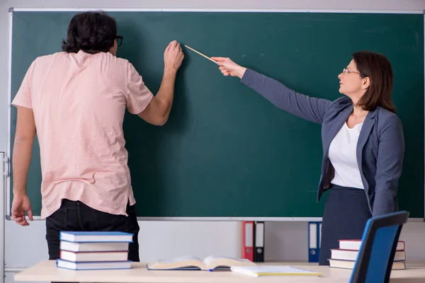 Old female teacher and male student in the classroom — Stock Photo, Image