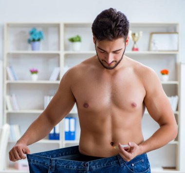 Kilo verme konseptinde büyük beden pantolon giyen bir adam.