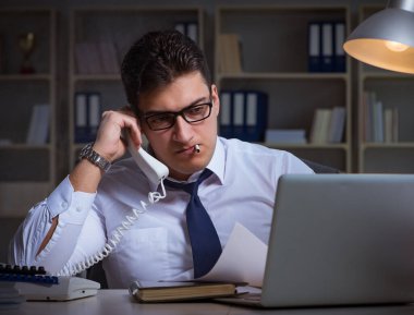 İş adamı telefonda konuşuyor ve ofiste sigara içiyor.