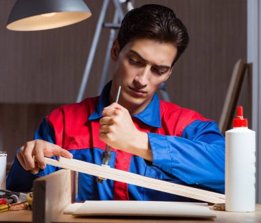 Genç adam ahşap parçaları diy konseptinde yapıştırıyor.