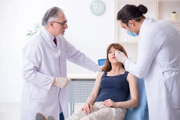 Deux médecins masculins et une jeune femme en chirurgie plastique concept — Photo