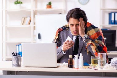 Ofiste grip olmuş bir adam çalışıyor.