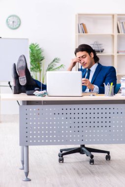 Genç işadamı ofiste oturuyor ve çalışıyor.