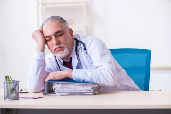 Old male doctor working in the clinic — Stock Photo, Image