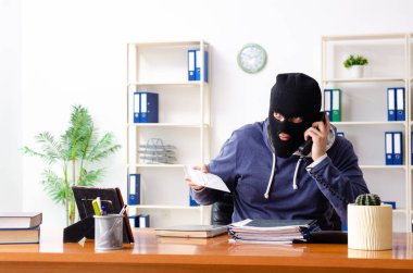 Male thief in balaclava in the office clipart