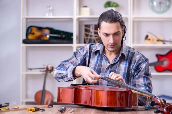 Jonge knappe reparateur die cello repareert — Stockfoto