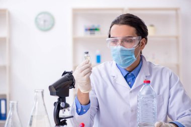 Genç erkek kimyager laboratuarda deney yapıyor.