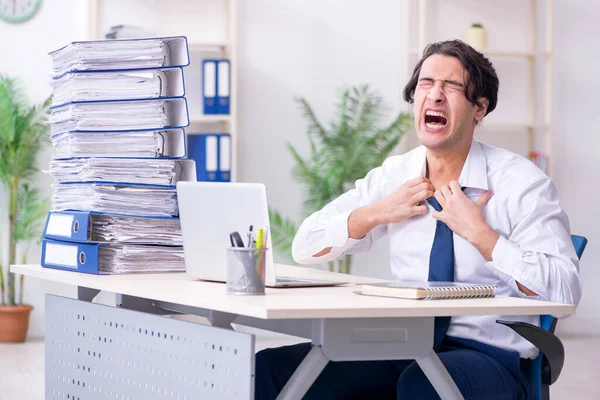 Joven empleado masculino infeliz con el trabajo excesivo — Foto de Stock