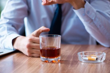 İş yerinde alkol ve sigara içen bir erkek işçi.