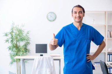 Klinikte çalışan genç erkek doktor.