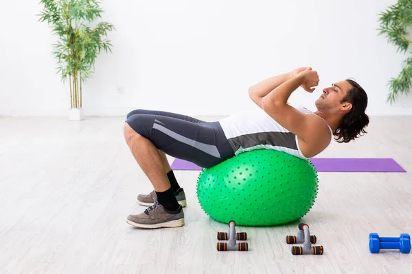 Young handsome man doing sport exercises indoors — Stock Photo, Image