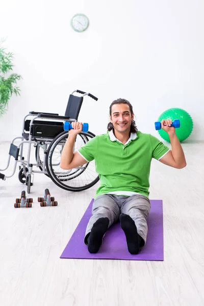 Young man in wheel-chair doing exercises indoors